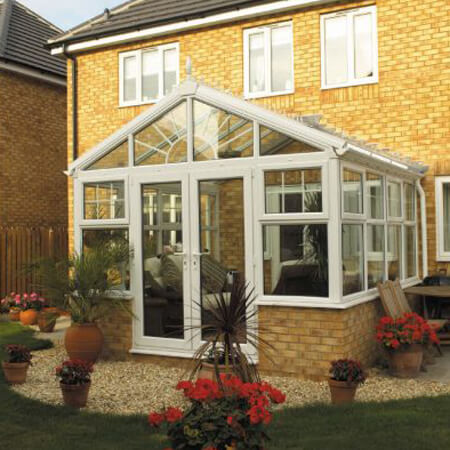 Bespoke Conservatories. White framed uPVC bespoke conservatory, square with an angled roof using a light brown dwarf wall.