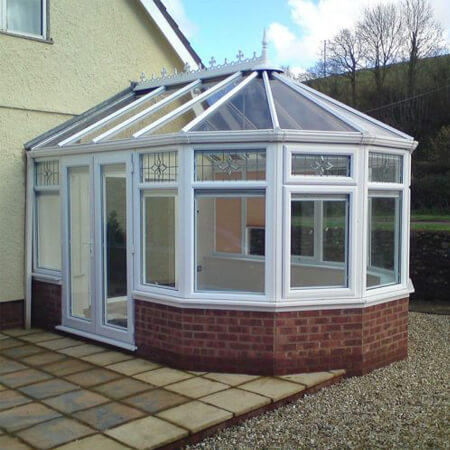 SW Plastic Victorian Conservatories. Victorian conservatory with a white frame and reddish dwarf wall.