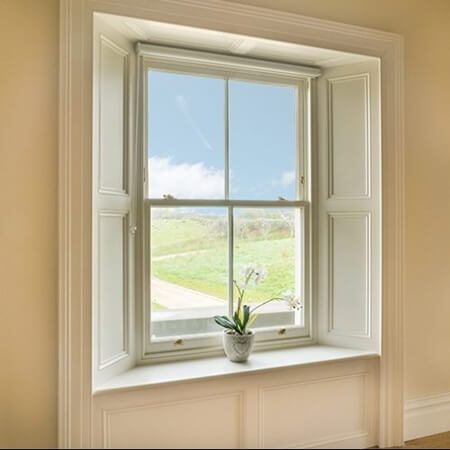 SW Plastic Windows. Off-white sash windows with 4 glass panels looking out onto a beautiful vista.